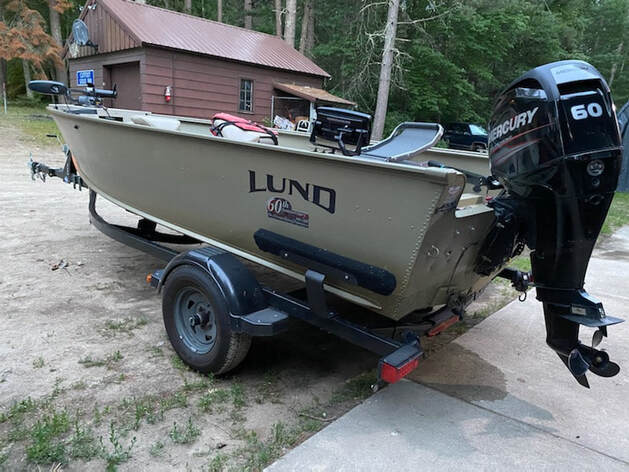 green Lund aluminum fishing boat with honda motor at the dock